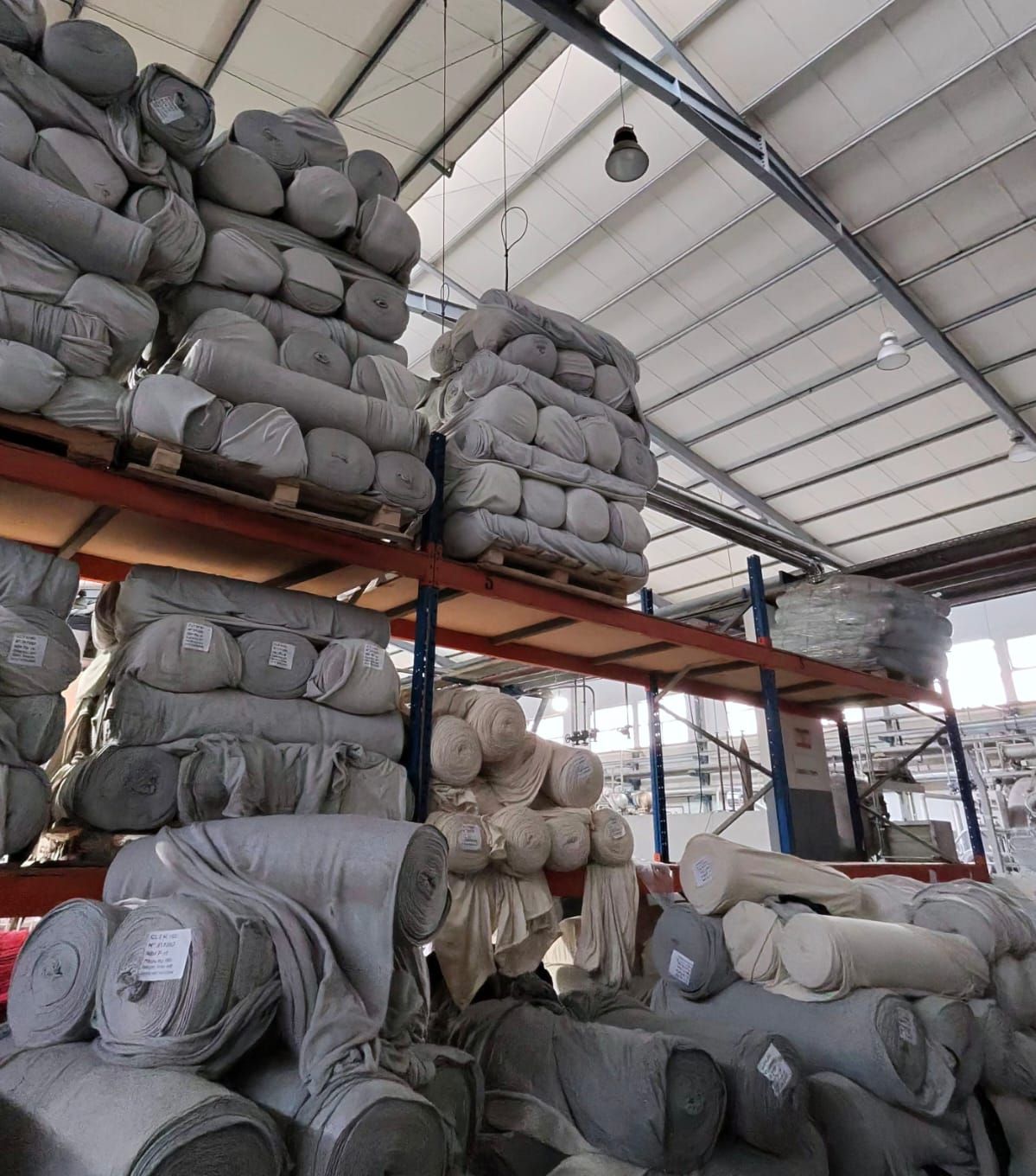 Rouleaux de tissu maille écru stockés sur rayonnages