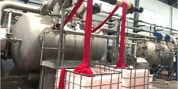 Tissu teint en rouge sortant d'une machine de teinture